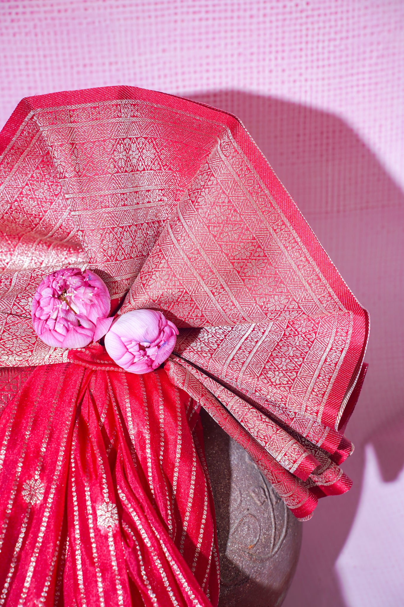 Red fabric with pink floral decorations on a textured pink background