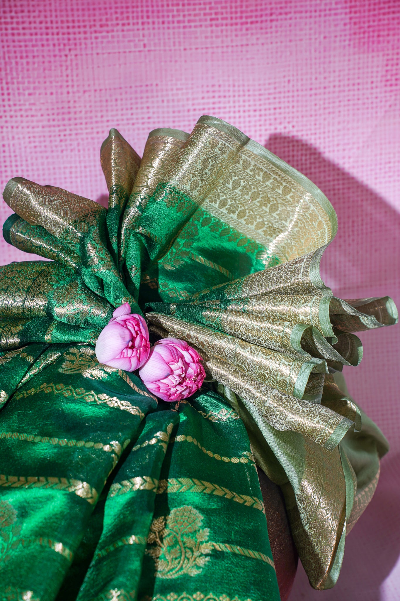 Green fabric with pink floral decorations on a pink background