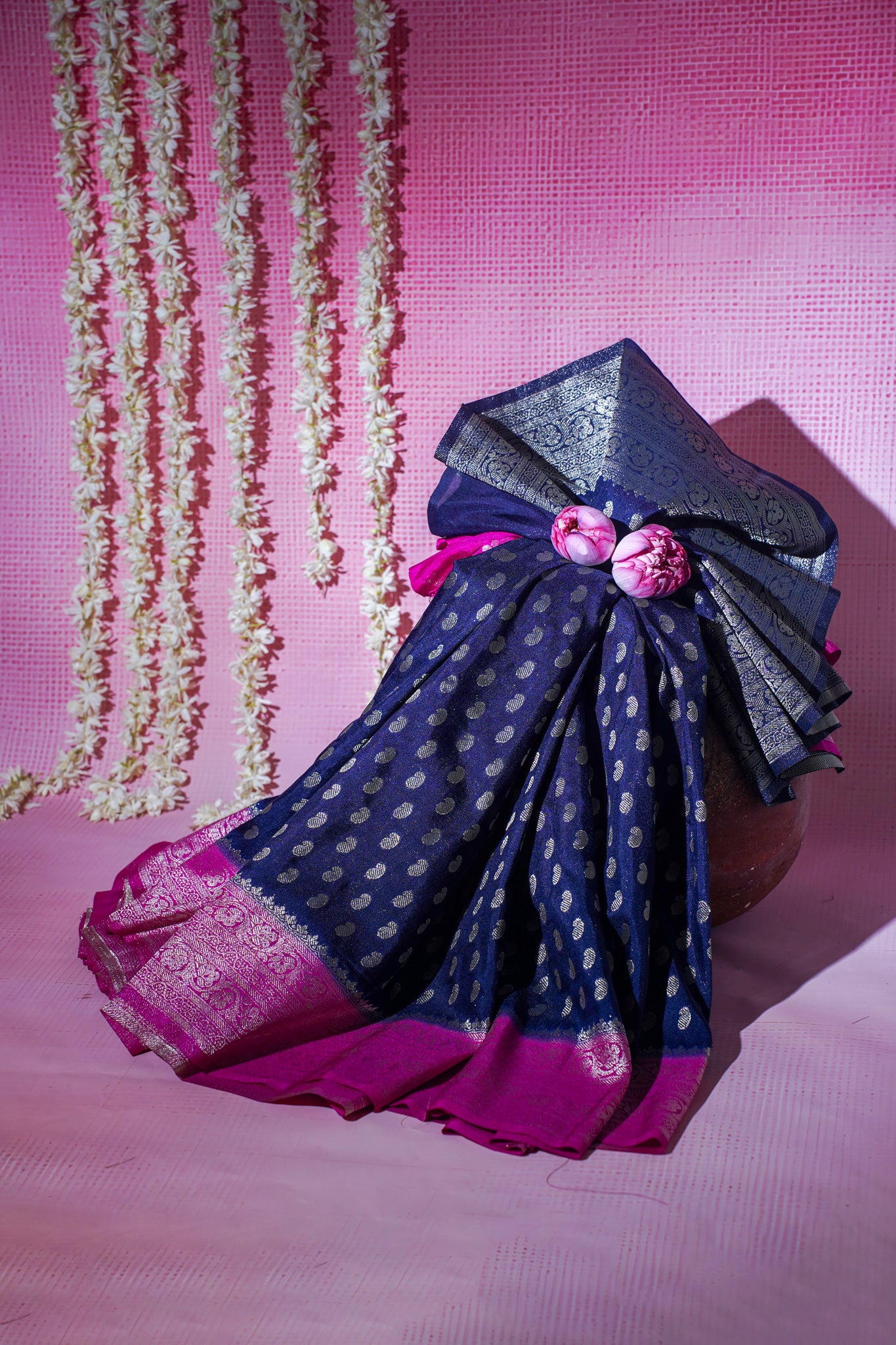 Navy and pink saree with decorative elements on a pink background
