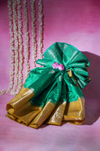 Green and gold saree with a pink flower on a pink background