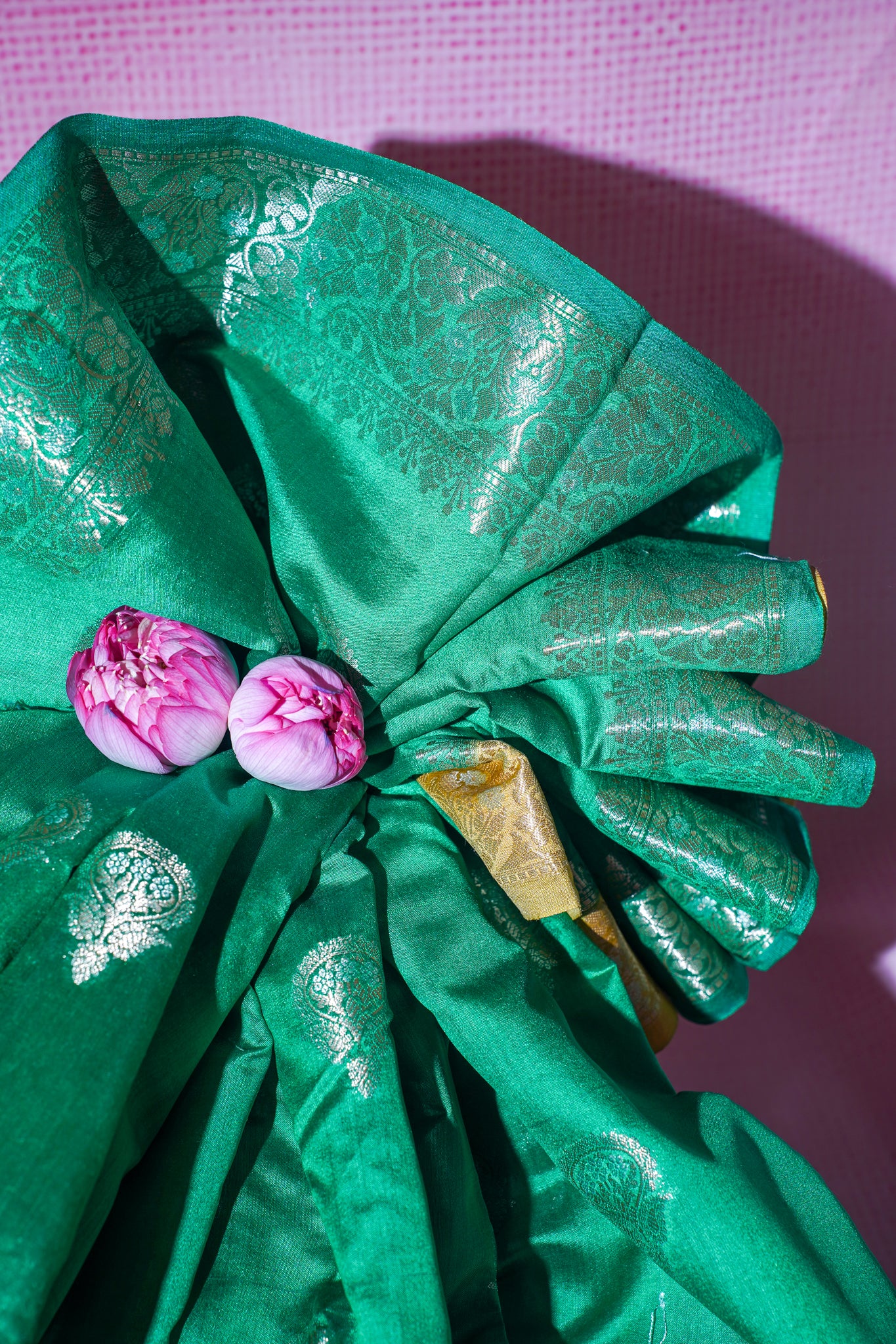 Green fabric with floral decorations on a pink background