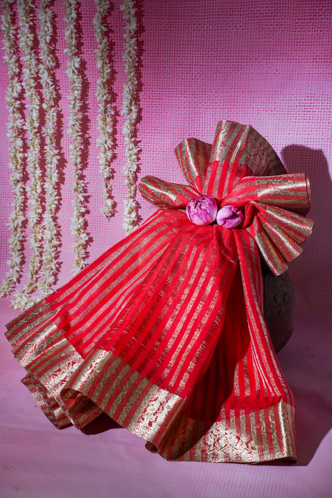 Decorative red and gold bow with a pink flower on a pink background