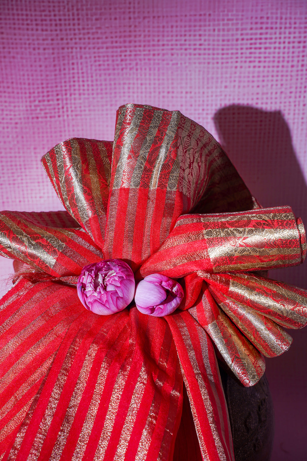 Red and gold striped bow with purple flowers on a pink textured background