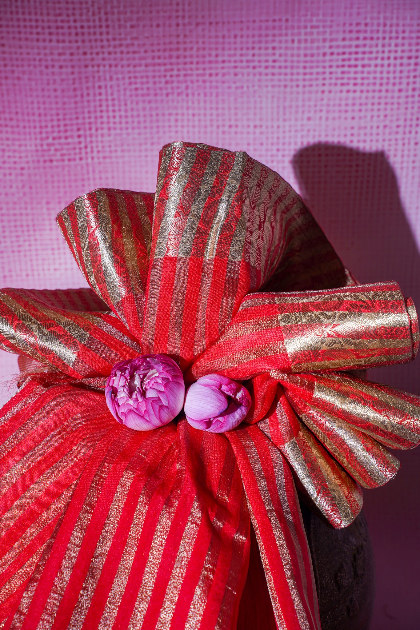 Red and gold striped bow with purple flowers on a pink textured background