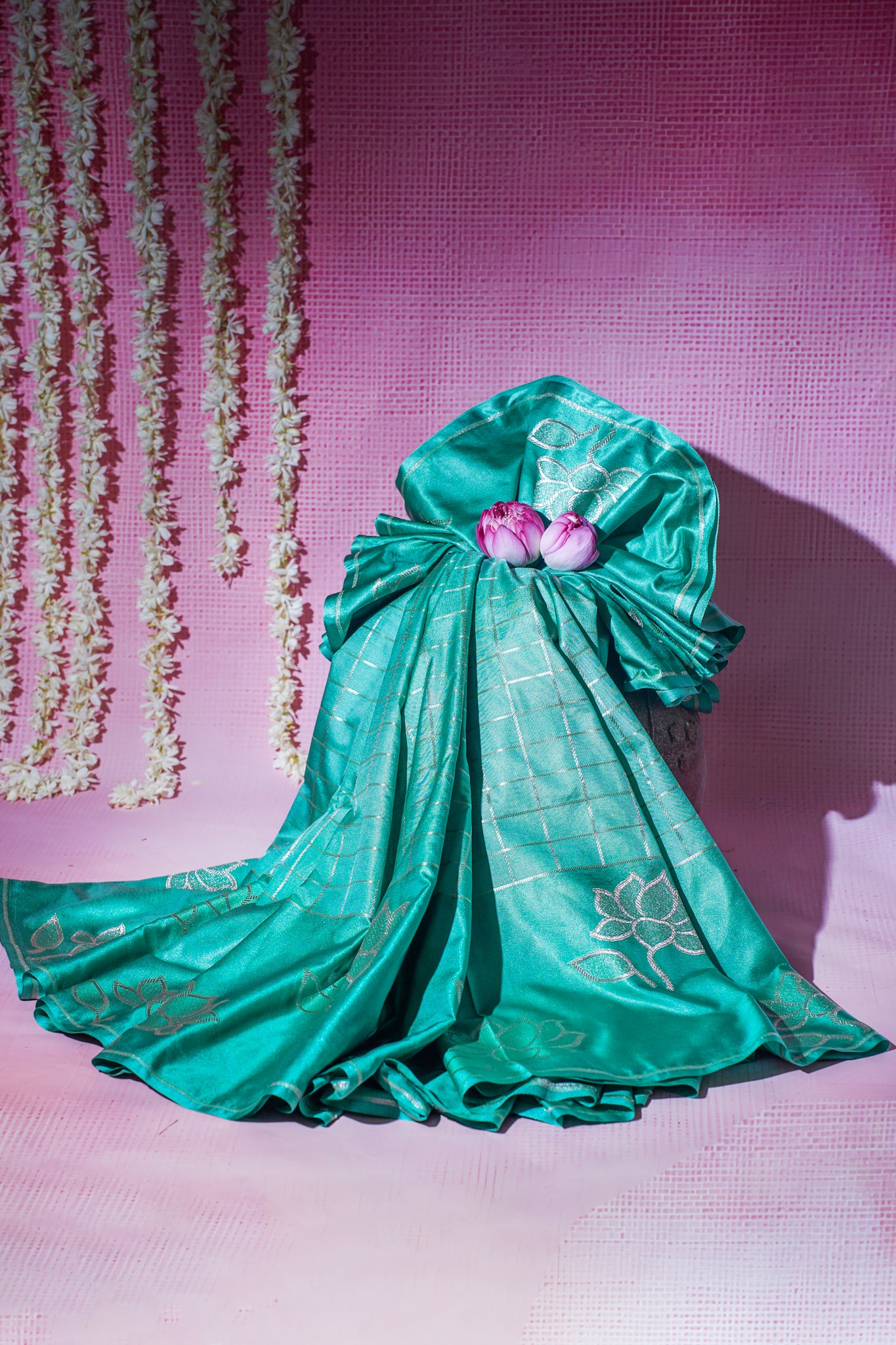 Green saree with floral decorations on a pink background