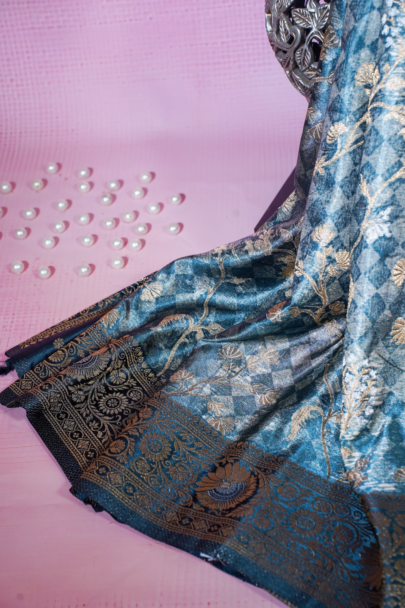 Blue and gold embroidered fabric on a pink background with pearls.