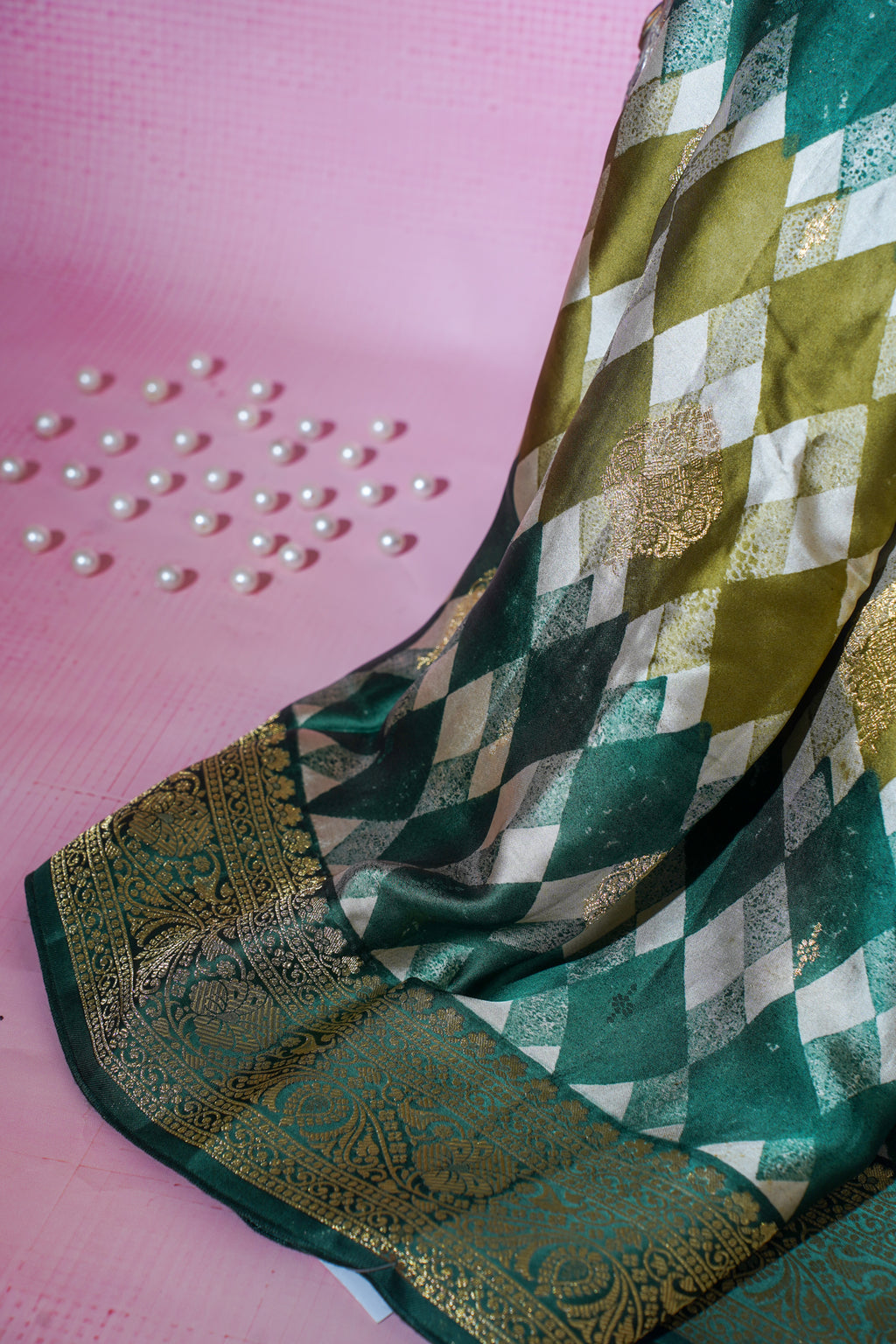 Green and gold patterned saree on a pink background