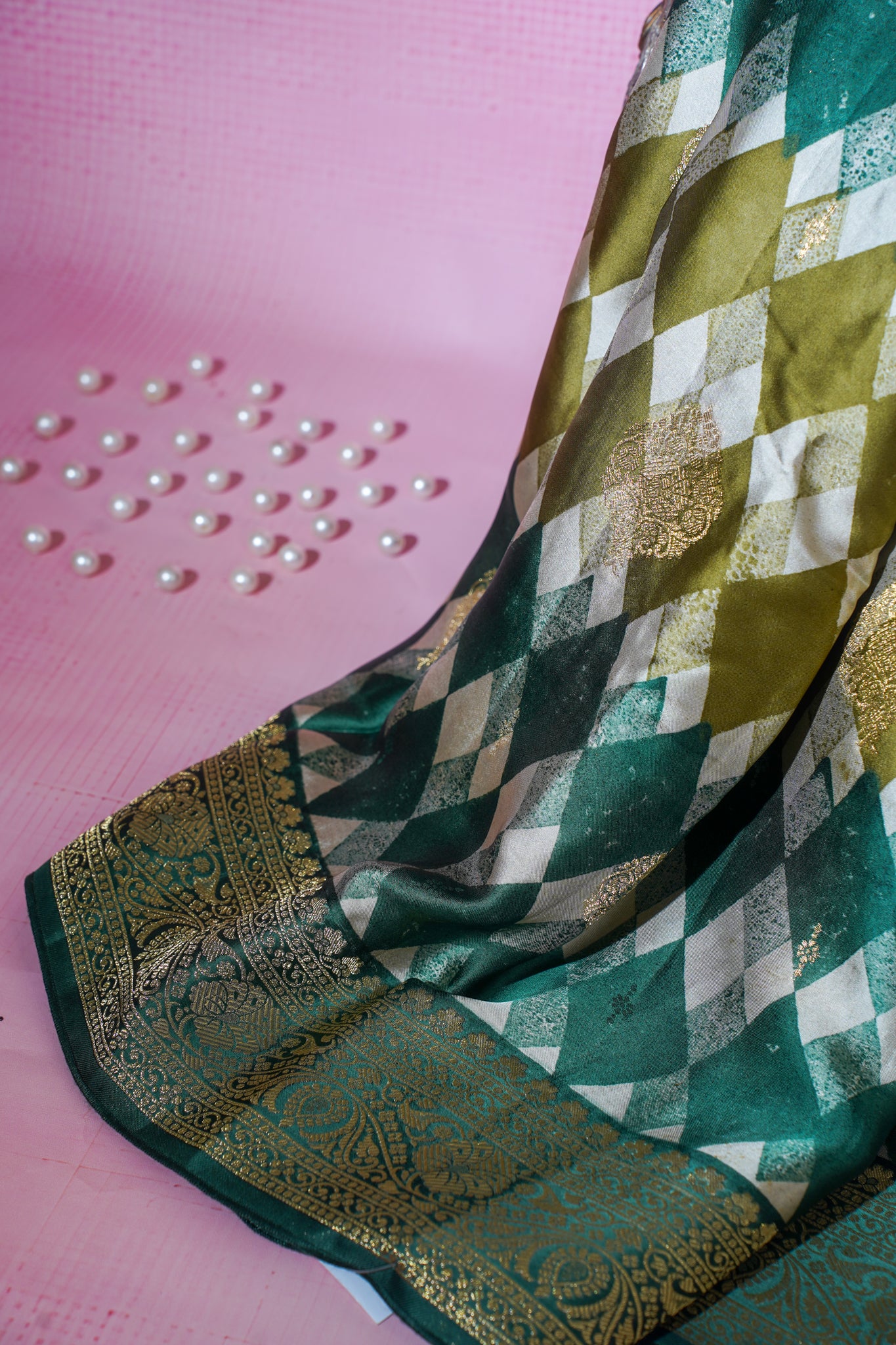 Green and gold patterned saree on a pink background