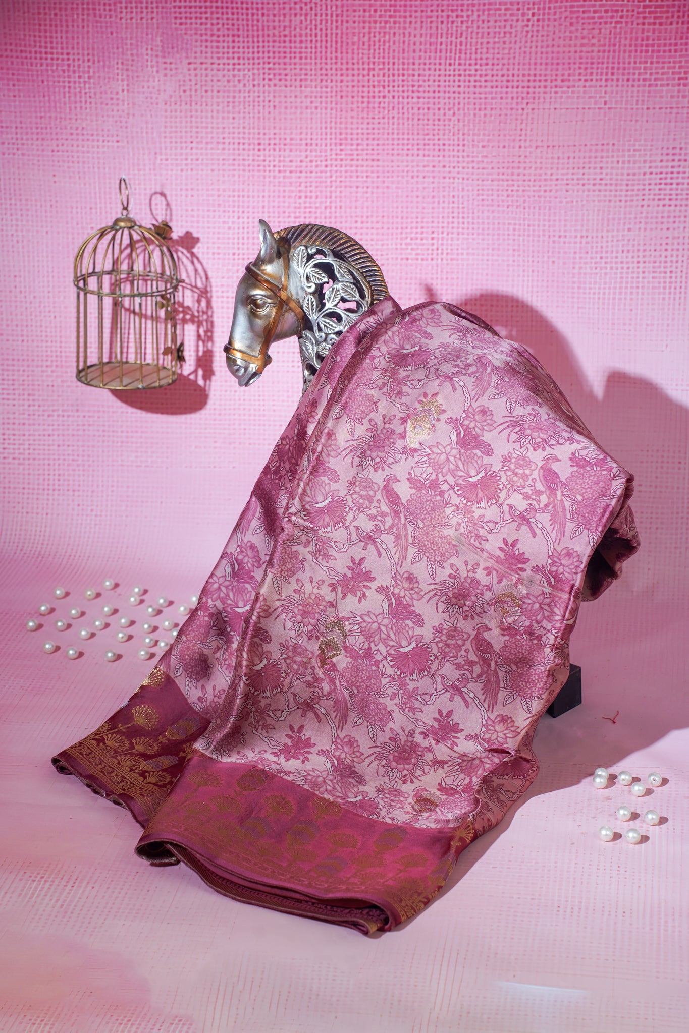 Pink floral saree with a horse head and birdcage on a pink background