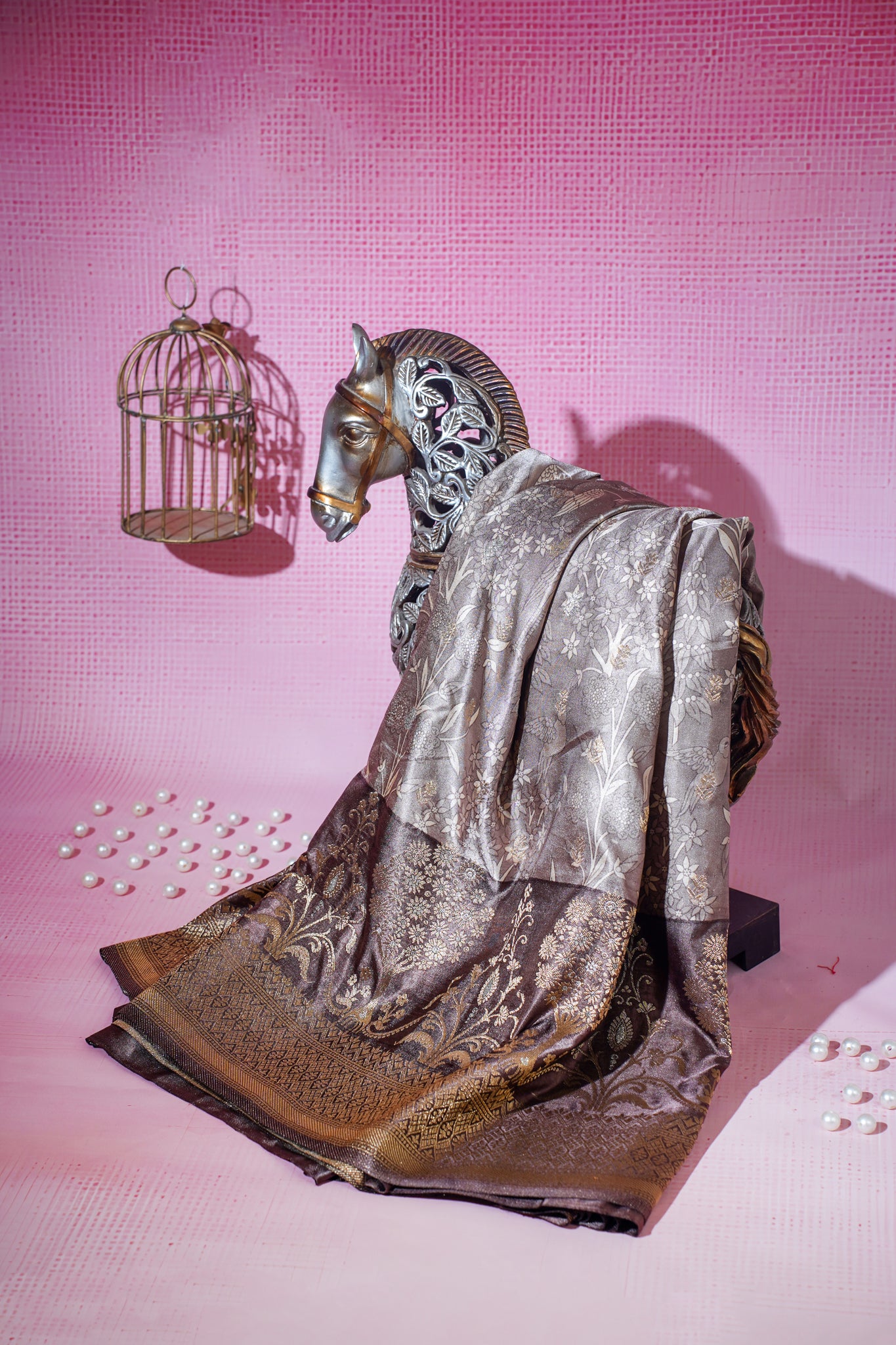 Decorative brown silk saree with horse sculpture with a birdcage on a pink background