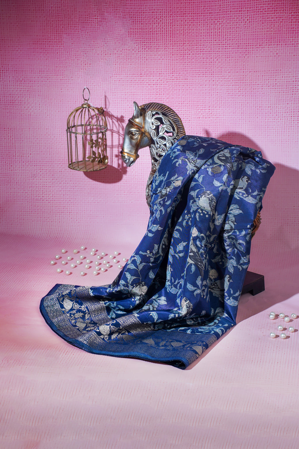 Blue floral-patterned fabric draped over a horse head sculpture on a pink background