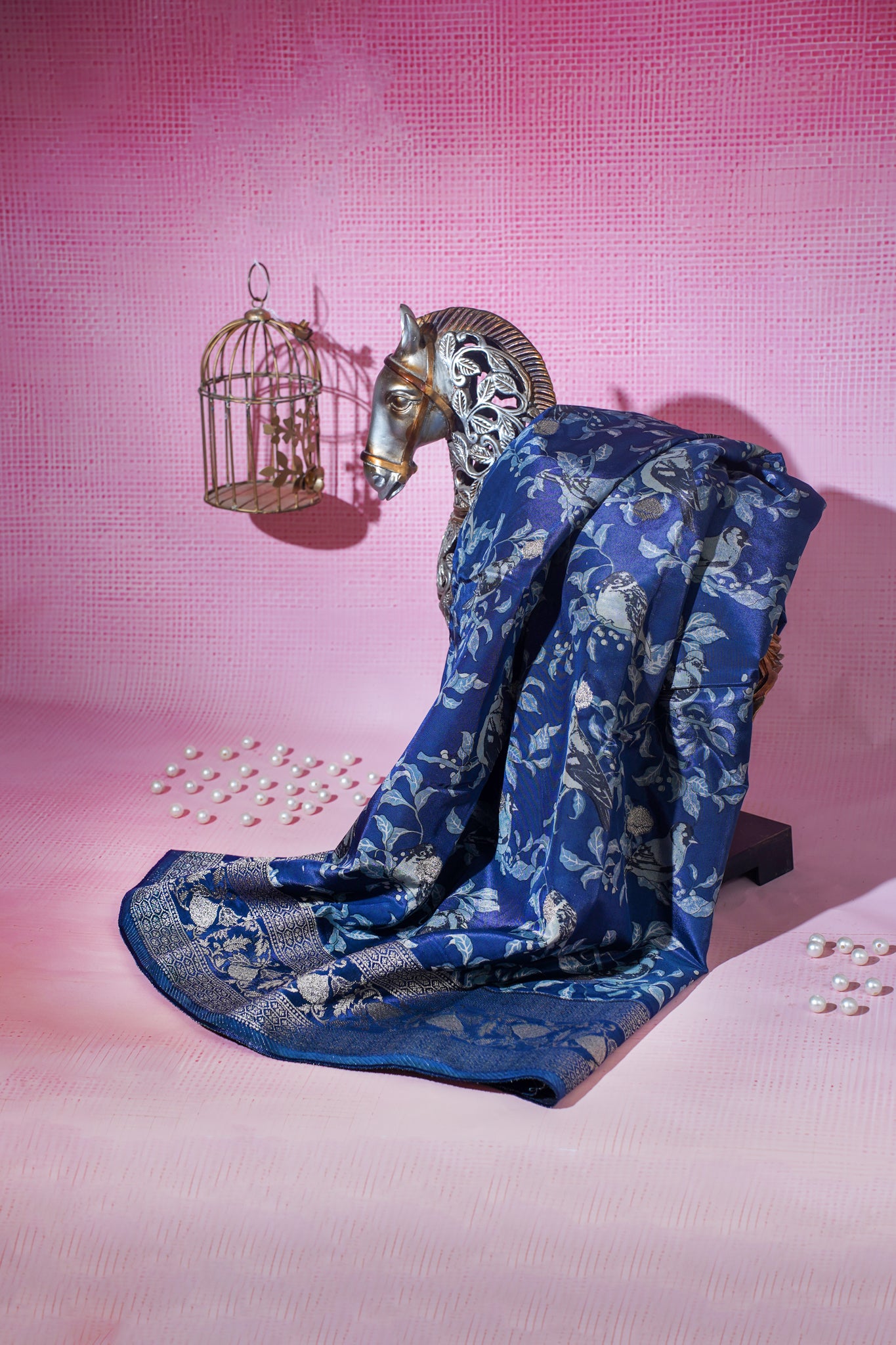 Blue floral-patterned fabric draped over a horse head sculpture on a pink background