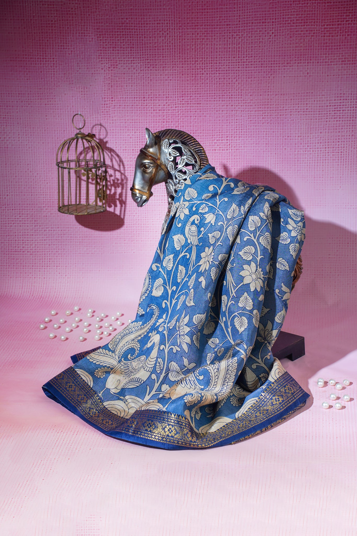 Decorative horse figurine with a blue floral-patterned cloth on a pink background