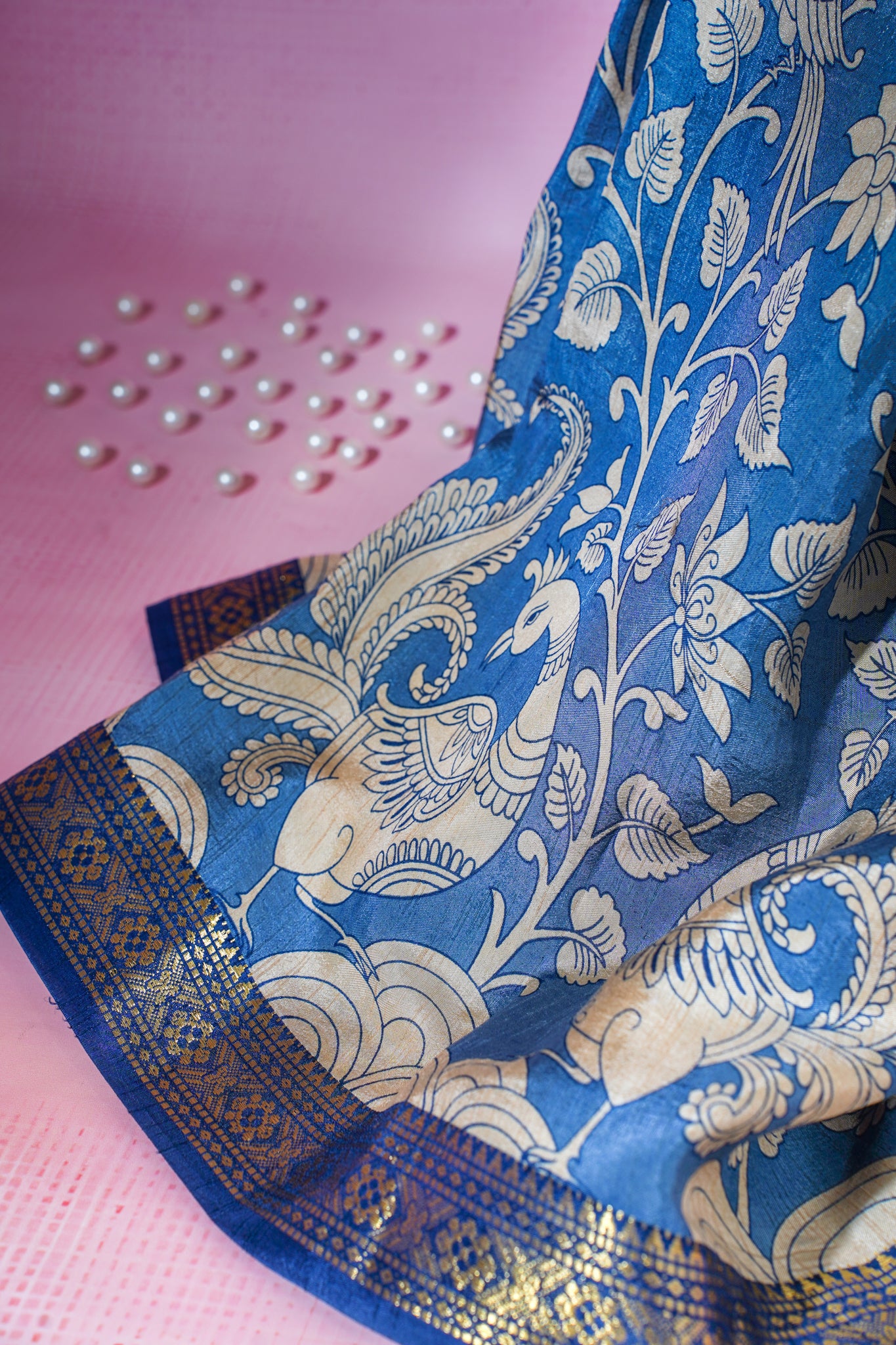 Blue saree with white floral and peacock design on a pink background