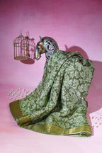 Decorative figurine of a goat draped in a green saree with a pink background