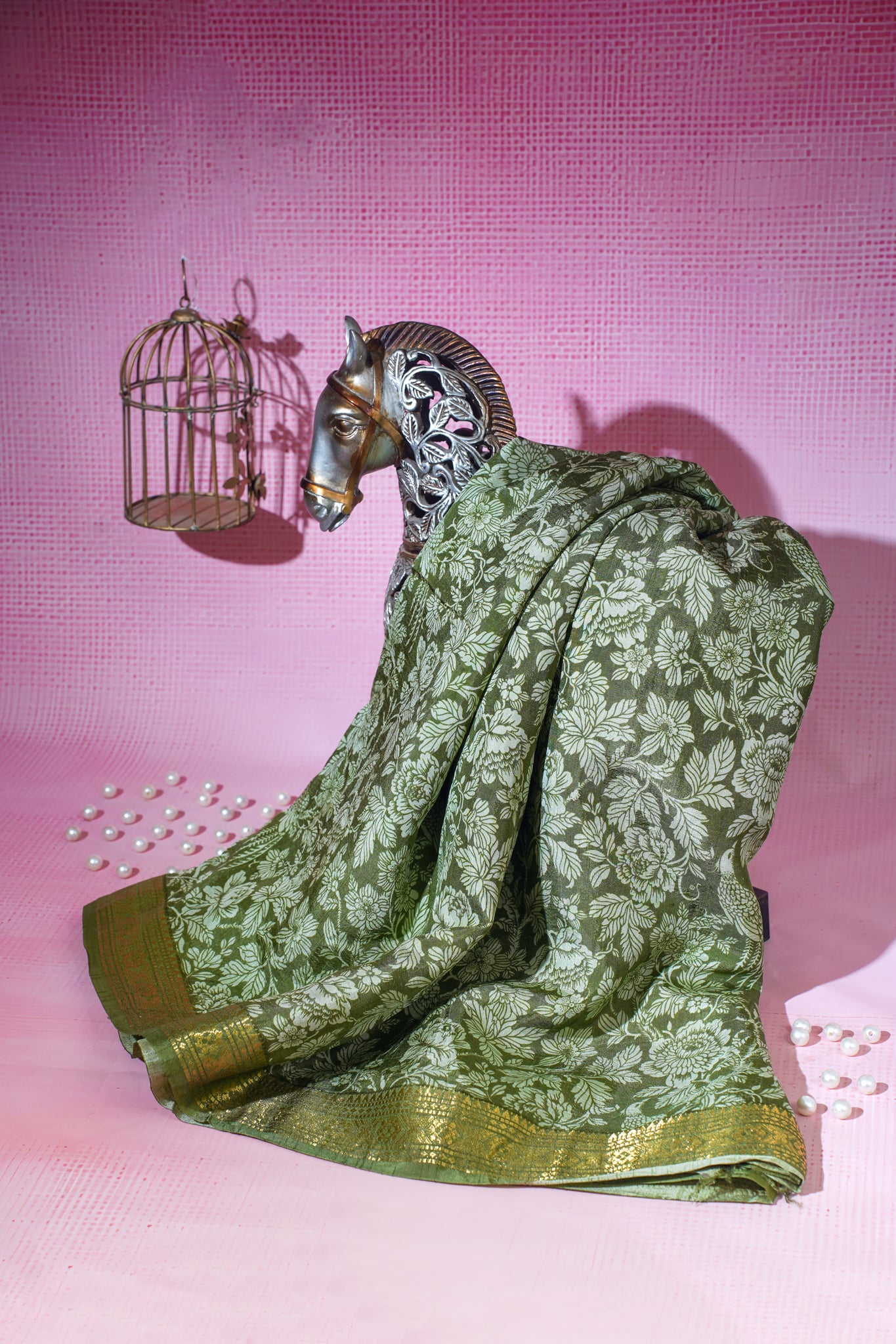 Decorative figurine of a goat draped in a green saree with a pink background