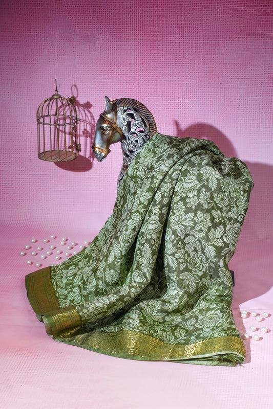 Decorative figurine of a goat draped in a green saree with a pink background
