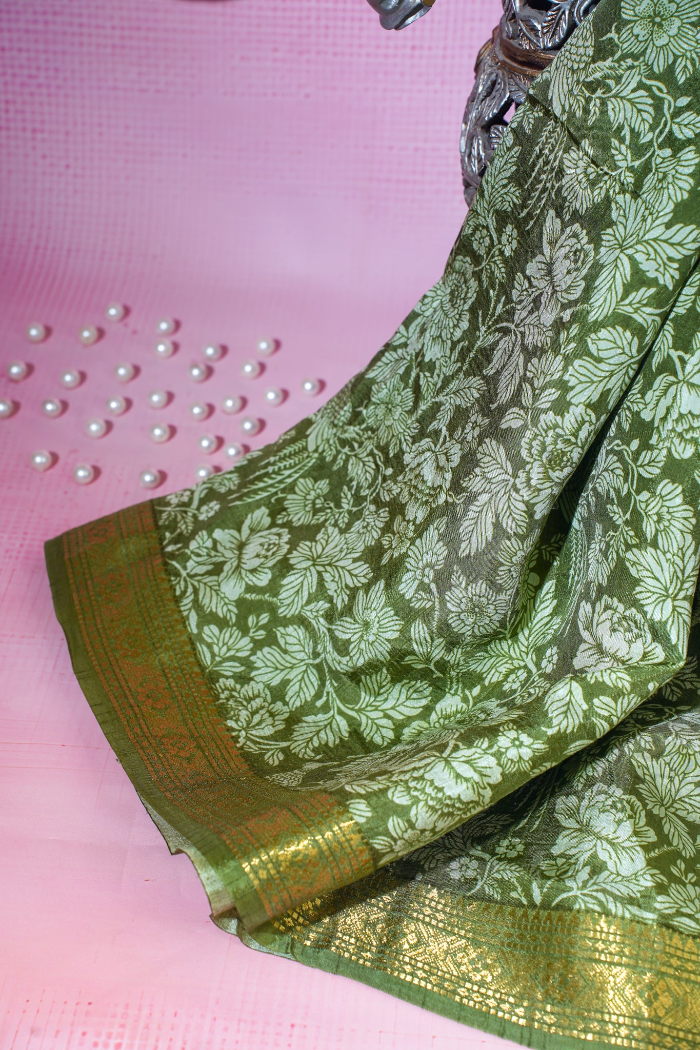 Green floral saree with gold border on a pink background